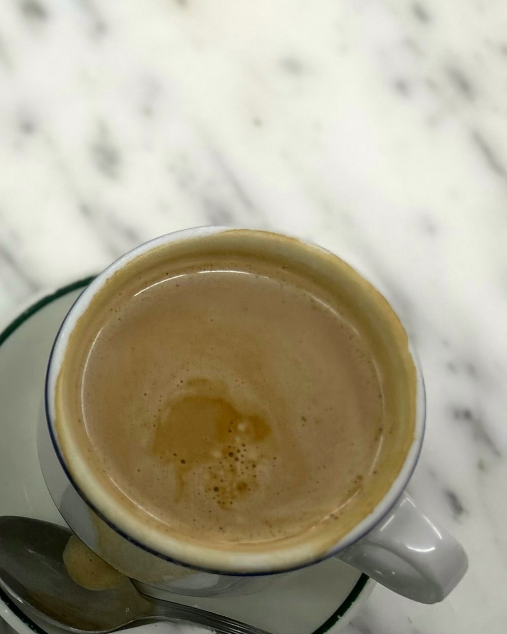 Café con leche en taza blanca sobre una barra de mármol
